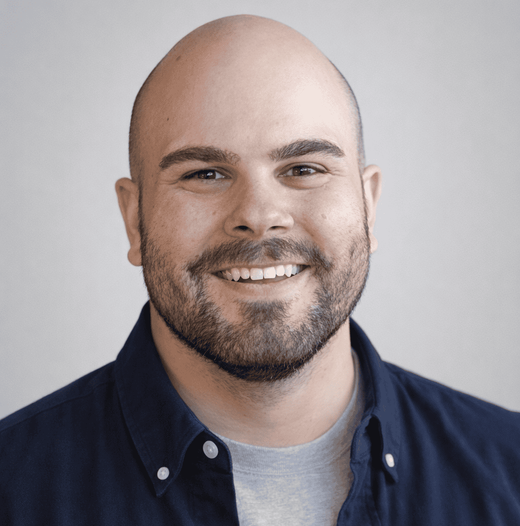 Smiling man with a beard wearing a navy blue shirt, representing health and wellness.