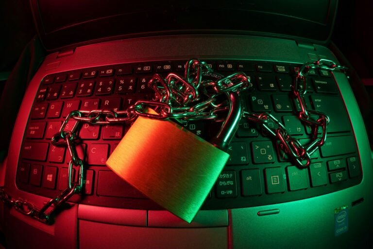 Padlock and chain locked across a laptop keyboard, representing ransomware locking a business out of its systems