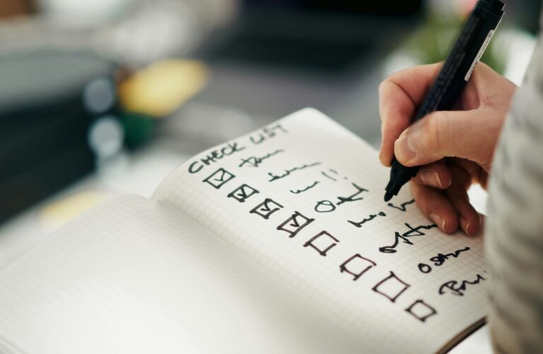 Hand checking off items on a handwritten checklist in a notebook